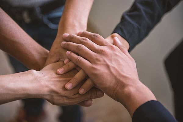Five multi-ethnic people with hands brought in